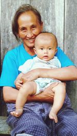 Portrait of grandmother and son against wooden wall