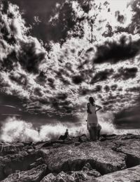 Rear view of woman standing by sea against sky