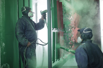 Painters spraying steel components in spray booth of a factory