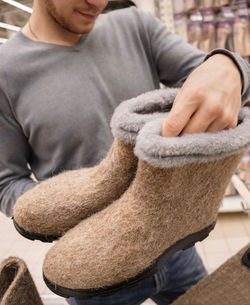 Man holds in his hands winter felt boots of beige color. selective focus.