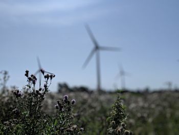 Wind turbines on field against sky