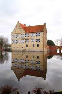 Reflection of building on lake against sky