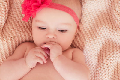 Cute baby girl lying in bed wearing flower headband in bed closeup. childhood. bed time.