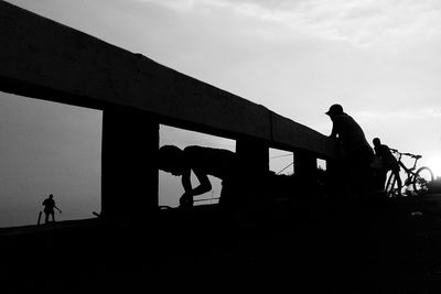 Silhouette people on bridge against clear sky