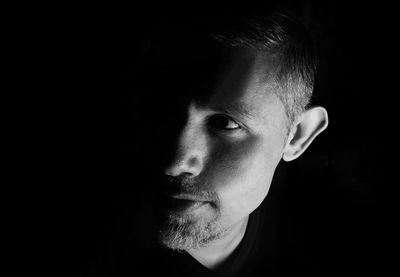 Close-up portrait of young man against black background