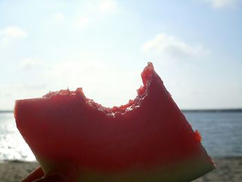 Close-up of hand holding ice cream against sky