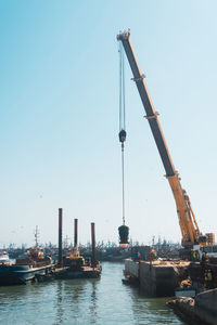 Cranes at commercial dock against clear sky