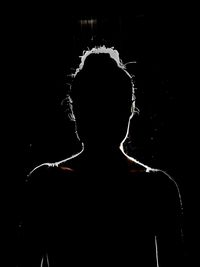 Rear view of silhouette man against black background