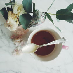 Directly above shot of leftover tea cup with spoon by flower vase on table