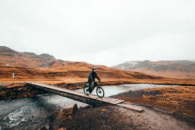 Man riding bicycle on mountain against sky