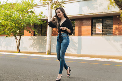 Full length portrait of woman standing on road in city