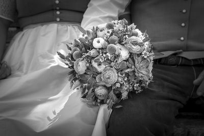 Close-up of woman holding bouquet against white wall