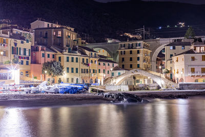 Illuminated buildings by sea at night