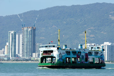 Ship in sea by city against sky