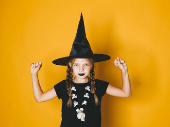 Portrait of smiling girl standing against yellow wall