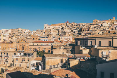 Cityscape against clear blue sky on sunny day