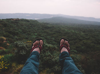 Low section of man on mountain against sky