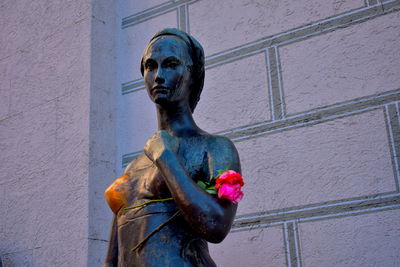 Statue of person holding sculpture against wall