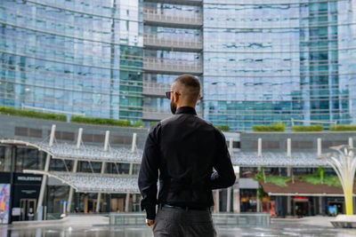 Rear view of woman standing against buildings in city