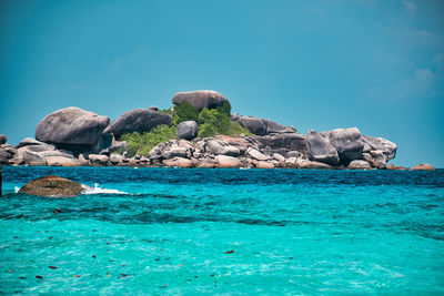 Rocks by sea against blue sky