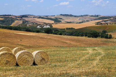 Hay bales on field against sky