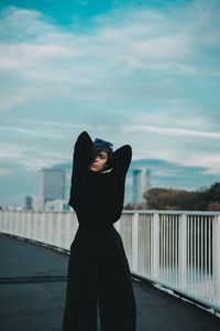 Woman standing by railing against sky