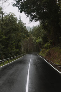 Road amidst trees in forest against sky