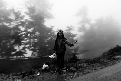 Full length of young woman standing against sky