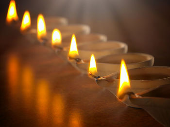 Close-up of lit diyas arranged on floor