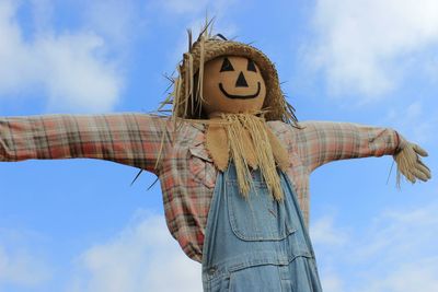 Low angle view scarecrow against cloudy sky