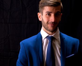 Portrait of young man against black background