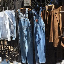 Bib overalls and coats hanging on metal at market stall