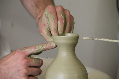 Cropped hands of potter making pot in workshop