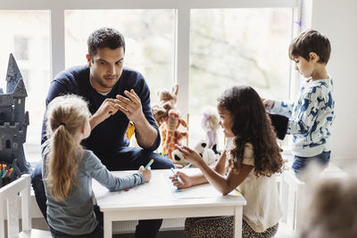 Male teacher with students in preschool