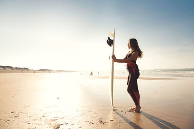 Woman holding umbrella on beach against sky