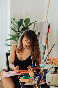 Woman painter focused on work sitting at table in her studio