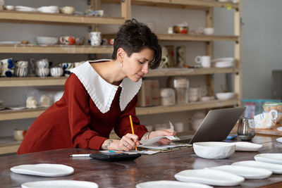 Side view of man using mobile phone while sitting on table