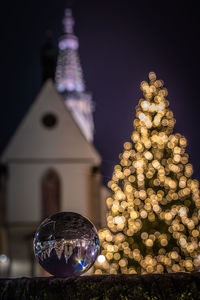Illuminated christmas tree against building at night