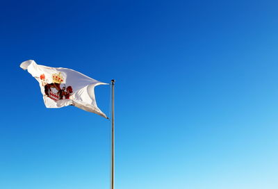 Low angle view of flag against clear blue sky