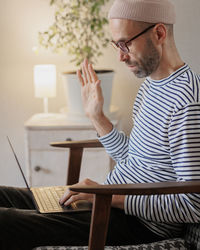 Side view of man talking on video call at home