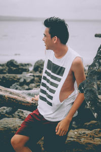 Young man sitting on rock at beach