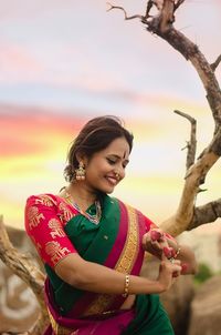 Smiling young woman standing against sky