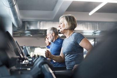 Group of fit seniors on treadmills working out in gym