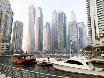 Boats moored in canal amidst buildings against sky