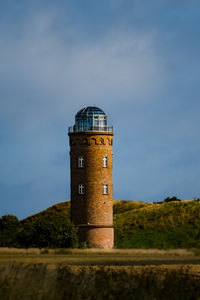 Lighthouse on field against sky