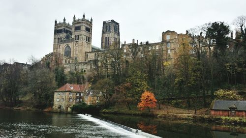 Low angle view of durham cathedral and river against clear sky