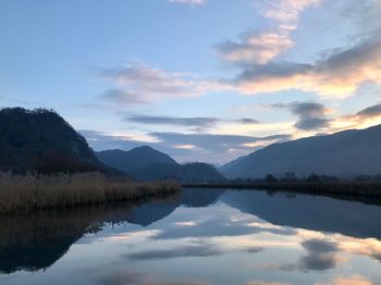 Scenic view of lake by mountains against sky during sunset