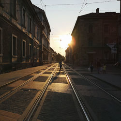 Railroad tracks amidst buildings in city during sunset