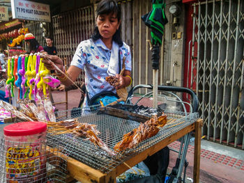 Female vendor with dried calamari for sale at footpath