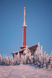 Telecommunication tower on lysa hora covered with snow and at orange-pink sunrise